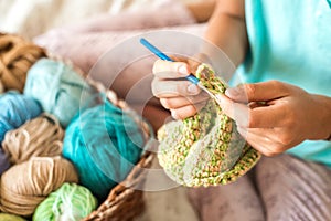 Girl knitting at home. Multi-colored balls of knitting thread in the basket. and a knitted white scarf