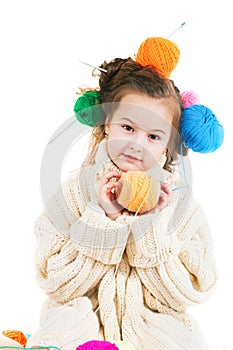 Girl with knitting spokes and balls of threads in hair