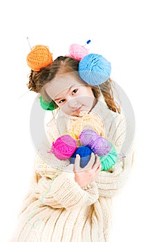 Girl with knitting spokes and balls of threads in hair