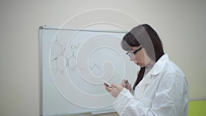Girl in lab coat writes on Board formula Tetrahydrocannabinol.