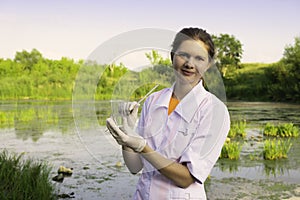 girl laboratory assistant looks at a sample of water in a test tube, recruited from the lake, the concept of ecology