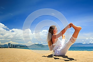 girl in lace in yoga asana full boat on beach