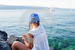 Girl by lake watching sailboats.