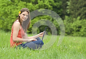 Girl with laptop relaxing on the grass