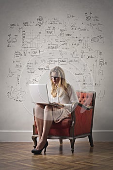 A girl with a laptop sitting on an armchair