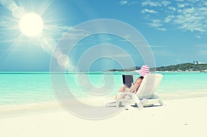 Girl with a laptop on the tropical beach