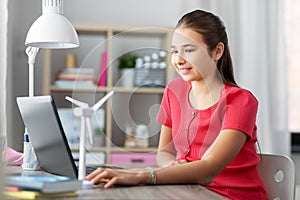 Girl with laptop and wind turbine toy at home