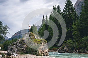 Girl on a large stone, a boulder, among the incredibly beautiful river of turquoise color, pine forest. summer day. Dolomites photo