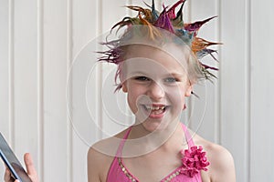 The girl laughs sincerely, holding a cell phone in her hands. The child looks primo into the lens. The girl is beautifully dressed