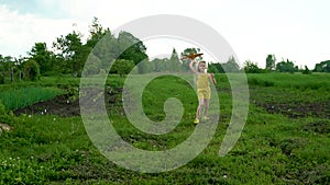 The girl launches up the plane against the background of green grass and blue sky with long blond hair on vacation.