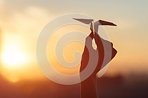 A girl is launching a paper airplane from a window at sunset. Support of the Telegram application and freedom internet. photo