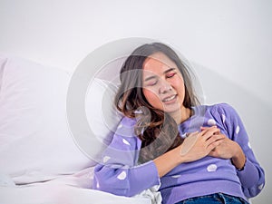 The girl lay in bed, using her hands to touch the chest. Severe heart pain, heart attack or cramping, painful chest compressions