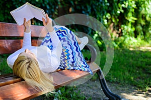 Girl lay bench park relaxing with book, green nature background. Woman spend leisure with book. Interesting book. Smart