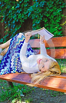 Girl lay bench park relaxing with book, green nature background. Woman spend leisure with book. Time for self