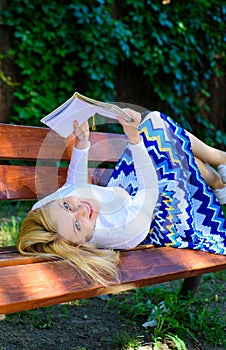 Girl lay bench park relaxing with book, green nature background. Woman spend leisure with book. Time for self