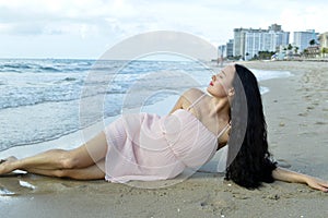 Girl laying on the beach in pink dress