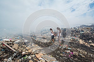 Girl leading her friend through the smoke at garbage dump
