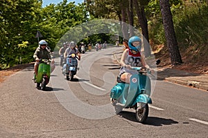 Girl leads a group of bikers riding a vintage italian scooter Vespa