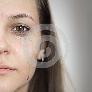 A girl with leaking mascara from tears. The girl is crying. Close up. Isolated