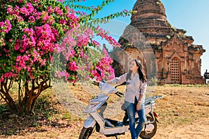 Girl leans on motorbike before ancient pagoda at Bagan