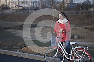 The girl leans on a parked bike. Rest on the spring cycle