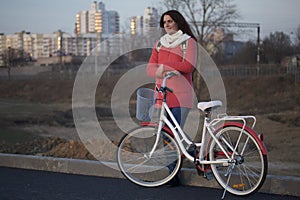 The girl leans on a parked bike. Rest on the spring cycle