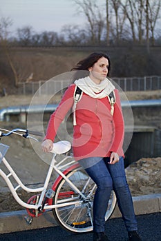 The girl leans on a parked bike. Rest on the spring cycle