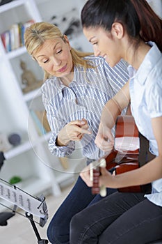 Girl learning how to play guitar with teacher