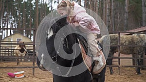 Girl is learning ride pony. Child gets on horse himself. Horse training. On farm