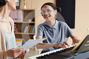 Girl learning to play piano with teacher