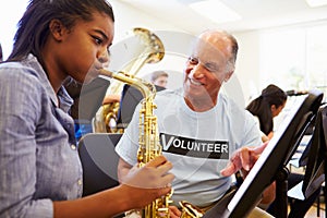 Girl Learning To Play Saxophone In High School Orchestra