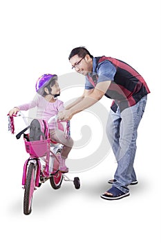 Girl learning to ride a bicycle with father