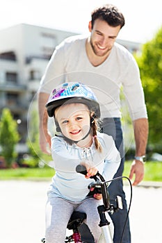 Girl learning to ride a bike with her father