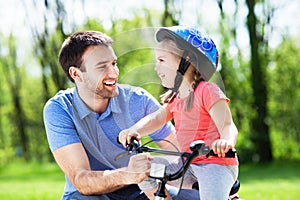 Girl learning to ride a bike with her father