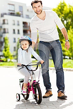 Girl learning to ride a bike with her father