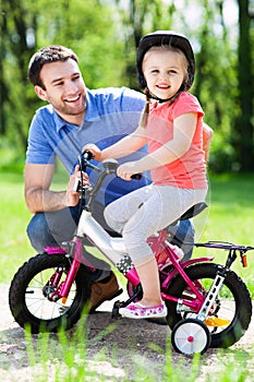 Girl learning to ride a bike with her father photo