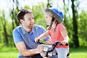 Girl learning to ride a bike with her father photo