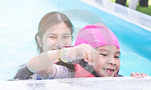 Girl is learning to swim on pool side