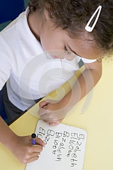 Girl learning to write name in primary class