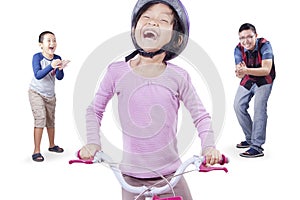 Girl learns riding a bike with dad and brother