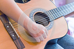 A girl learns to play guitar at home close up on hands