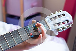 A girl learns to play guitar at home close up on hands