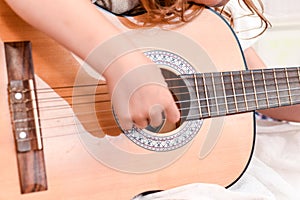 Girl learns to play guitar during a music lesson on the instrument