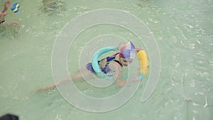 Girl learns to swim in the pool. A girl in a swimming suit swims with a circle in an indoor pool in a kindergarten.