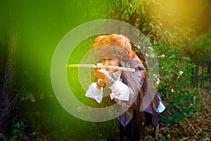 Girl in a leather jacket, a big red fox fur hat and with a crossbow in the forest in autumn. A female model poses as a