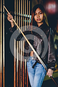 Girl in leather jacket preparing to play billiard