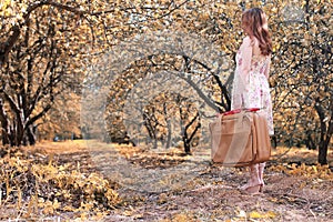 Girl with leather suitcase for travel in the autumn park on walk