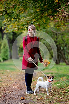 Girl with leaves walki the doge in park alley