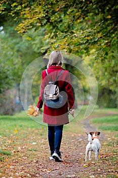 Girl with leaves walki the doge in park alley