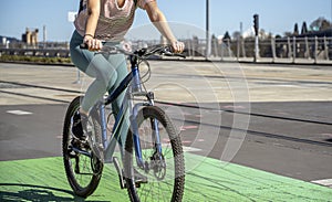 Girl in leggings rides a bicycle with a backpack behind her while riding a green bike path at the Tilikum Crossing Bridge in